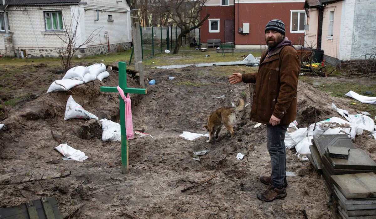 A man stands next to a grave
